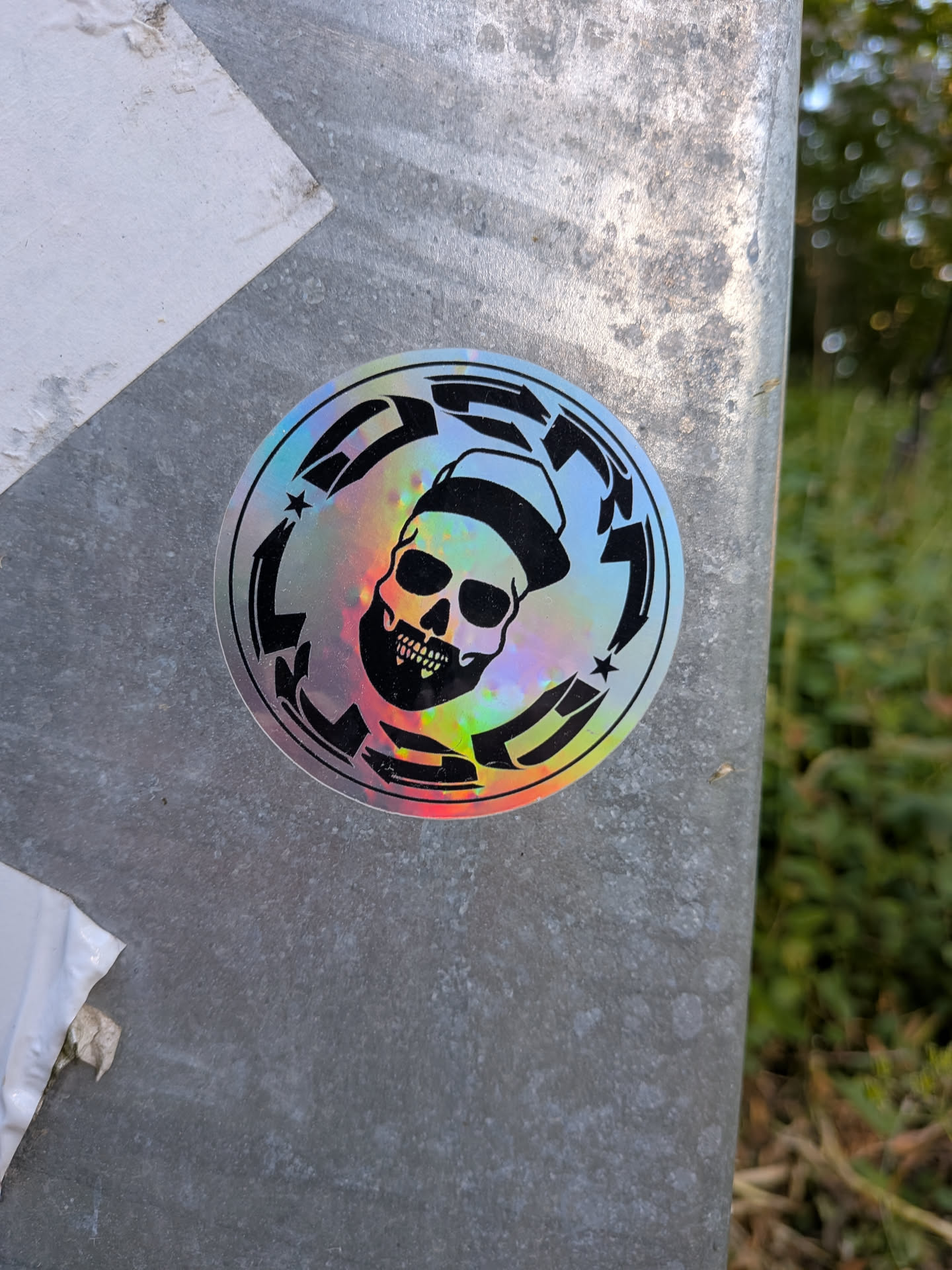 A circular holographic sticker with a black print of a bearded skull wearing a cap, enclosed by a circular border containing the stylized word 'DESTROY'.