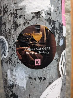 Street sticker Circular sticker showing a cocktail glass in a dim bar setting. Features white Swedish text asking 'Vågar du dejta utan alkohol?' and a pink 'IQ' logo at the bottom.