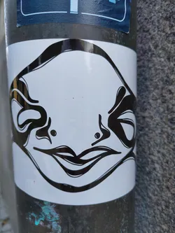 Black and white sticker featuring an abstract illustration of a face with a prominent mouth and flowing lines. The style is reminiscent of surrealism or psychedelic art.
