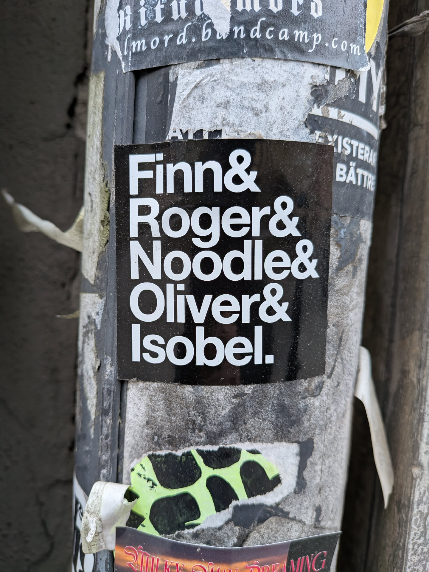 The sticker is a black square with five names written in white, bold, sans-serif font, stacked vertically. Each name is followed by an ampersand, except for the last name, 'Isobel', which is followed by a period. The text is centered on the black background, creating a high-contrast and minimalist design.