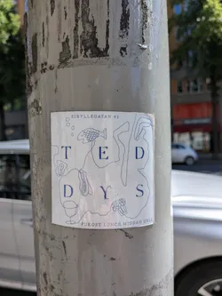 Street sticker A roughly square sticker with slightly rounded corners, featuring a white background and dark blue (almost navy) text and line art. The word 'TEDYS' is prominently displayed in capital letters, arranged somewhat irregularly across the center. Surrounding and intertwined with the letters are thin, continuous line drawings depicting a fish at the top, a wine glass at the bottom left, and a cluster of berries or grapes at the bottom right. Several abstract, organic shapes and small circles are also scattered throughout the design. At the top, the address 'SIBULLEGATAN 43' is written, and at the bottom, 'FUKOST LUNCH MIDDAG DELI' indicates meal services.