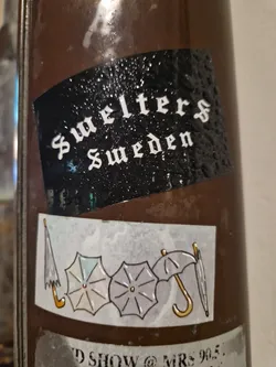 A sticker featuring the text Swelters Sweden on a black background, and another sticker with three umbrellas on a brown background. There's also some text partially visible at the bottom that seems to mention a show and a location (MRS 905).