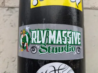 Street sticker A sticker featuring the logo of RLV MASSIVE Studio. The logo includes a cartoon leprechaun playing a keyboard, along with the studio name in stylized green lettering on a gray background. The style is reminiscent of a music studio or record label.