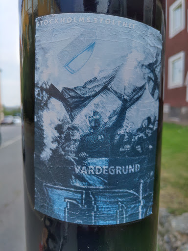 Street sticker A sticker featuring a stylized image, possibly referencing Stockholm's history or culture. The central motif appears to be a historical scene with figures and a boat, rendered in shades of blue and grey.  The text 'Vardegrund' is visible at the bottom.