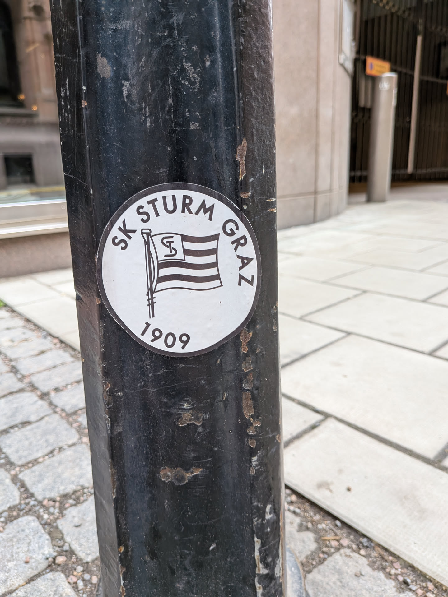 A circular black and white sticker featuring the SK Sturm Graz logo, depicting a striped flag with an 'S' emblem, the club name, and the founding year 1909.