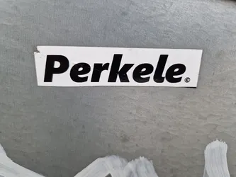 Street sticker A simple, rectangular sticker with the word 'Perkele.' printed in bold, uppercase, black letters on a white background. The sticker shows minor wear and tear.