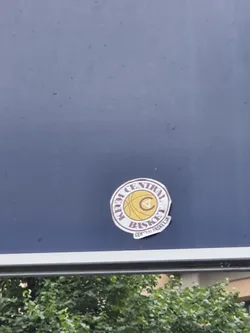 Street sticker Round sticker with a basketball and the text "Kem Central Basket" and a logo. The sticker is placed on a blue surface.