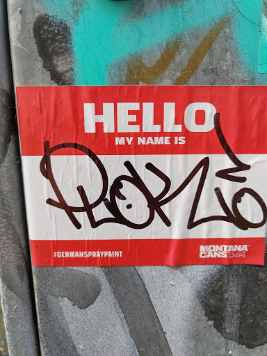 A red and white sticker imitating a name tag. It has the text 'HELLO MY NAME IS' followed by a graffiti tag that reads 'Rok20'. At the bottom, it has the hashtags '#germanSpraypaint' and the Montana Cans logo.