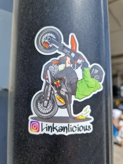 Street sticker A cool sticker featuring a stylized illustration of a stunt rider performing a wheelie on a KTM dirt bike. The sticker has a unique design with a flame effect and the artist's Instagram handle.
