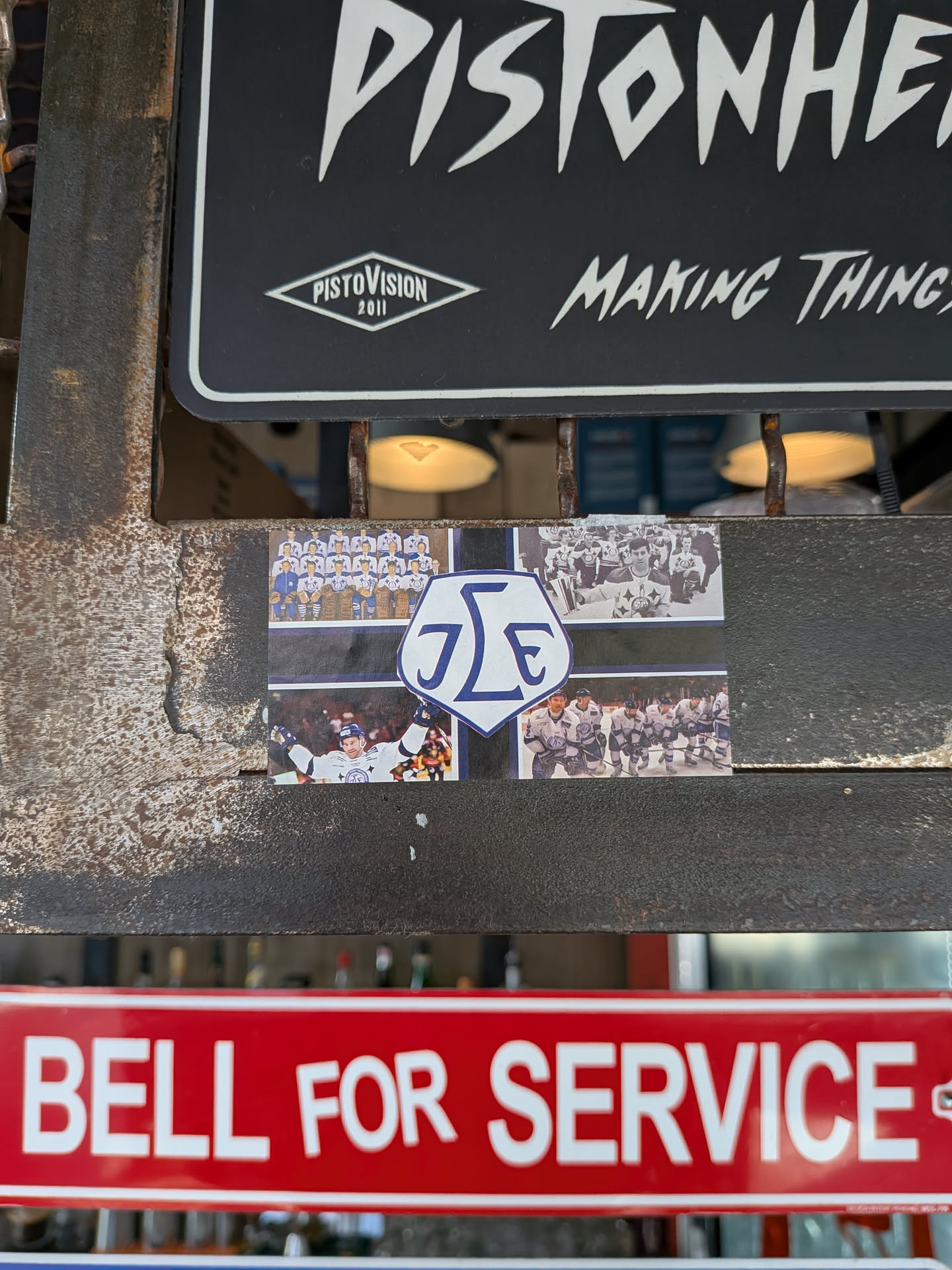 Rectangular sticker featuring a collage of four hockey photos (team shot, trophy celebration, goal celebration, on-ice action) surrounding a central blue and white shield logo with the letters 'JLE'.