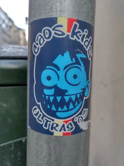 Street sticker A sticker featuring a cartoon illustration of a blue-faced kid with large eyes and sharp teeth. The text 'Chaos Kid' is arched at the top, and 'Ultras' is at the bottom. There are colored stripes at the very top and bottom of the sticker.
