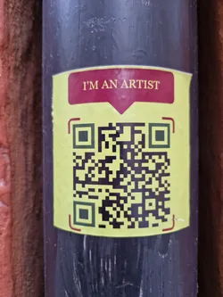 A yellow and maroon sticker with a QR code. The text on the sticker says, "I'm an artist."