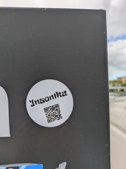 Street sticker The sticker is a white circle with the text "Insonika" in a gothic style font at the top. Below the text is a QR code.