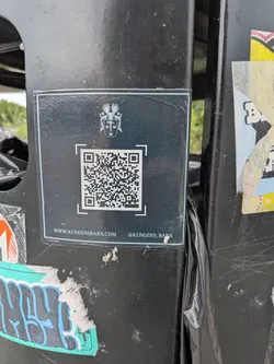 Street sticker Square black sticker featuring a white heraldic crest, a central QR code, a website URL, and an Instagram handle.