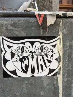 Street sticker Black and white sticker featuring a stylized cat face with a mischievous grin. The word "MAN" is incorporated into the design. 