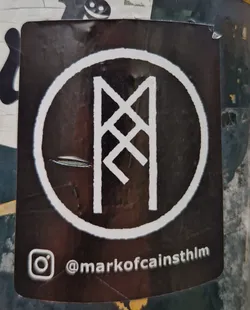 Street sticker A round black and white sticker with a white rune symbol in the center. The Instagram handle @markofcainsthlm is visible at the bottom of the sticker.