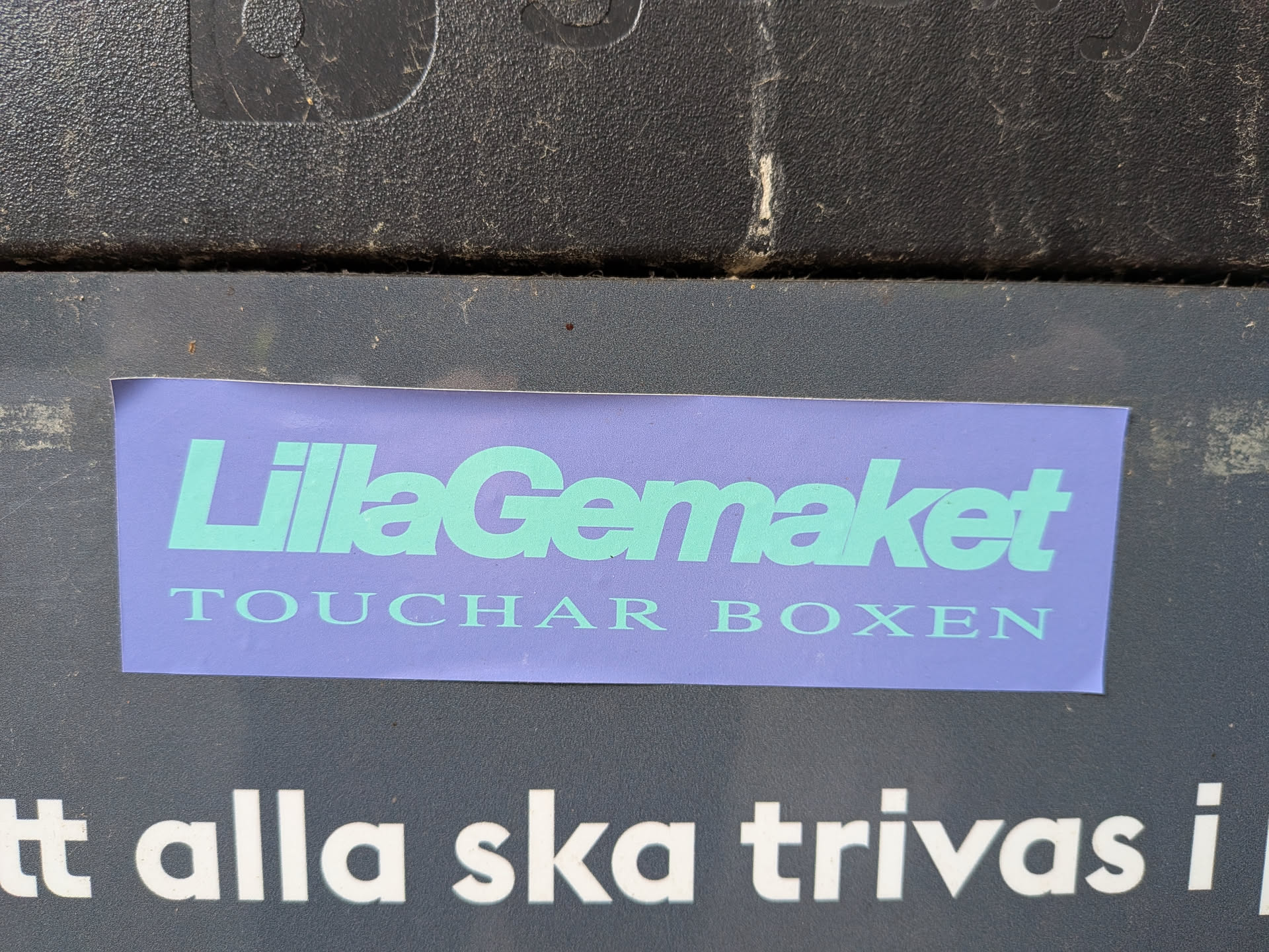 A rectangular lavender sticker featuring mint green text. The top line reads 'LillaGemaket' in a bold sans-serif font, and the bottom line reads 'TOUCHAR BOXEN' in a smaller, spaced serif font.