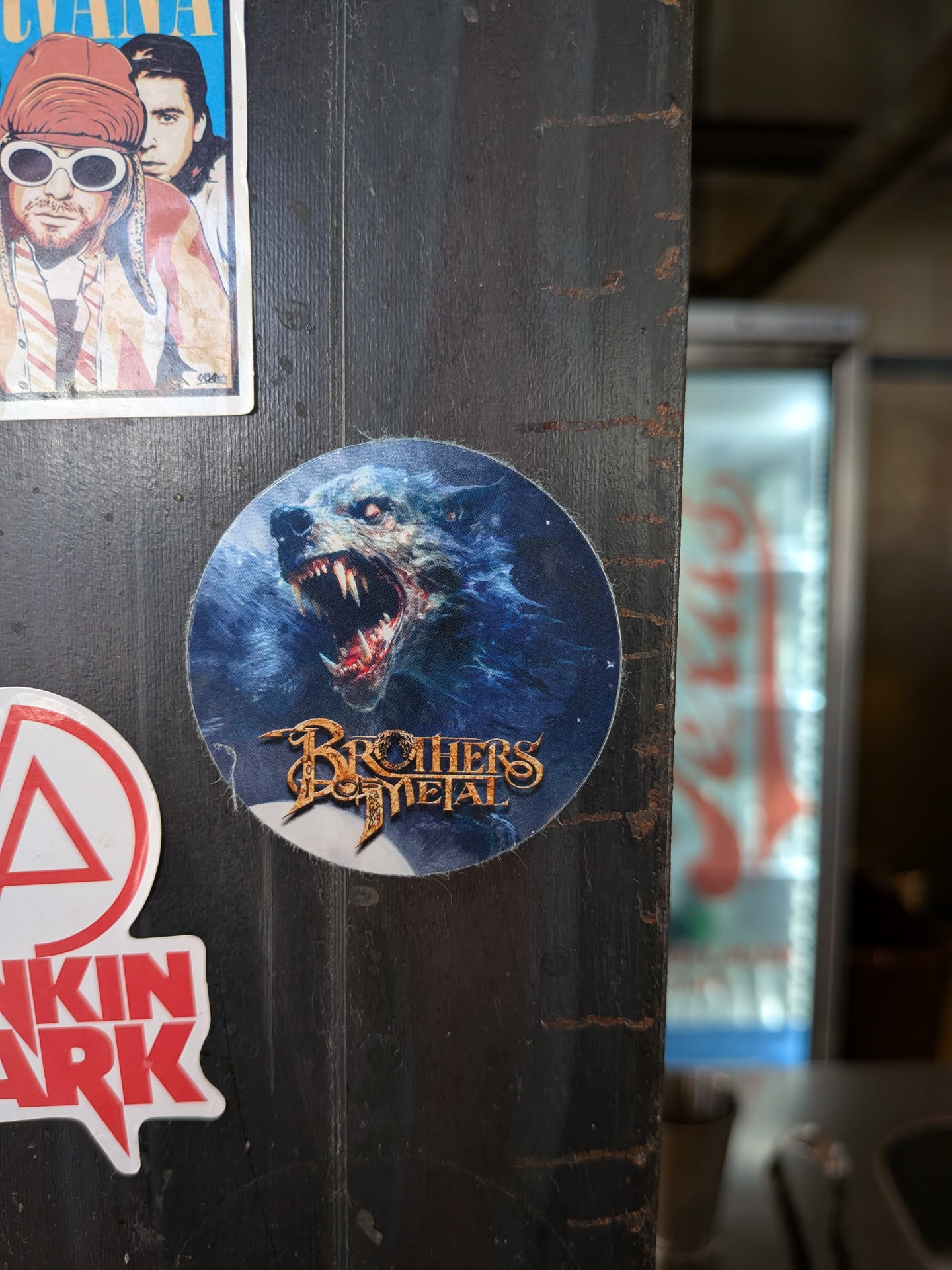 Circular sticker showing a snarling blue werewolf with glowing eyes and sharp fangs. The band name 'Brothers of Metal' is written in a stylized gold font at the bottom.