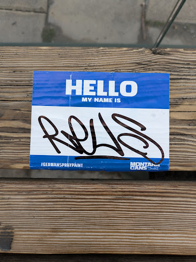 A blue name tag sticker with the text 'HELLO MY NAME IS' and a graffiti signature 'RQLS'. The sticker also features the logos for German Spray Paint and Montana Cans.