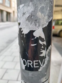 A black and white sticker with a portrait and the word "FOREVER" at the bottom. The sticker is partially damaged and peeled off.