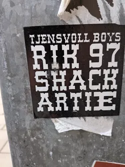 Street sticker A square black sticker featuring white text in a bold, Western-style serif font. The text is stacked in four lines on a solid black background, reading 'TJENSVOLL BOYS', 'RIK 97', 'SHACK', and 'ARTIE'.
