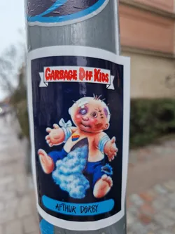 Street sticker Sticker featuring Arthur Dorby from the Garbage Pail Kids series.  The sticker shows a baby with injuries, in a style reminiscent of the original Garbage Pail Kids cards.