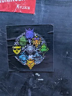 Street sticker The sticker is square, predominantly black, featuring a circular arrangement of eight distinct, stylized animal heads. Each animal is rendered in bright, often neon, colors against a white, intricate, organic, and somewhat skeletal background pattern that forms the circular frame. In the center of the circle is a white wolf with blue eyes and a spiked collar. Clockwise from the top, the animals include a purple lynx with pointed ears, an orange fox with a pink and blue bow, a green frog wearing a green bucket hat adorned with an alien symbol, a dark blue/grey raven or crow, a yellow owl with bright blue eyes, a light blue shark, a yellow bear wearing black sunglasses, and another green bear wearing a green bucket hat. Geometric shapes like triangles and chevrons in various colors (purple, yellow, green, blue) are integrated into the design, often highlighting or framing the individual animal portraits. The overall aesthetic is modern, colorful, and edgy.