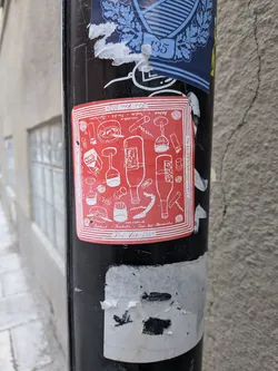 Street sticker A square red sticker with white line art illustrations, depicting various wine-related items such as wine bottles, wine glasses, corkscrews, bottle openers, and corks. The illustrations are arranged in a whimsical, scattered pattern. Text is present around the border and within the design, including event details and names. The sticker has a thin white border with multiple parallel lines, giving it a framed appearance. It is affixed to a black pole, showing some minor wear and tear.