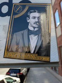 Street sticker The sticker features a stylized, monochrome portrait of a man from a bygone era. He is depicted with slicked-back hair, a prominent mustache, and is dressed in formal attire, including a suit jacket, crisp white shirt, and a bow tie. The portrait is framed by an ornate gold border with decorative elements. Above the portrait, on the left side, is a blue and gold crest with the text 'AIK 1891+'. The overall aesthetic is reminiscent of vintage advertising or historical illustrations.