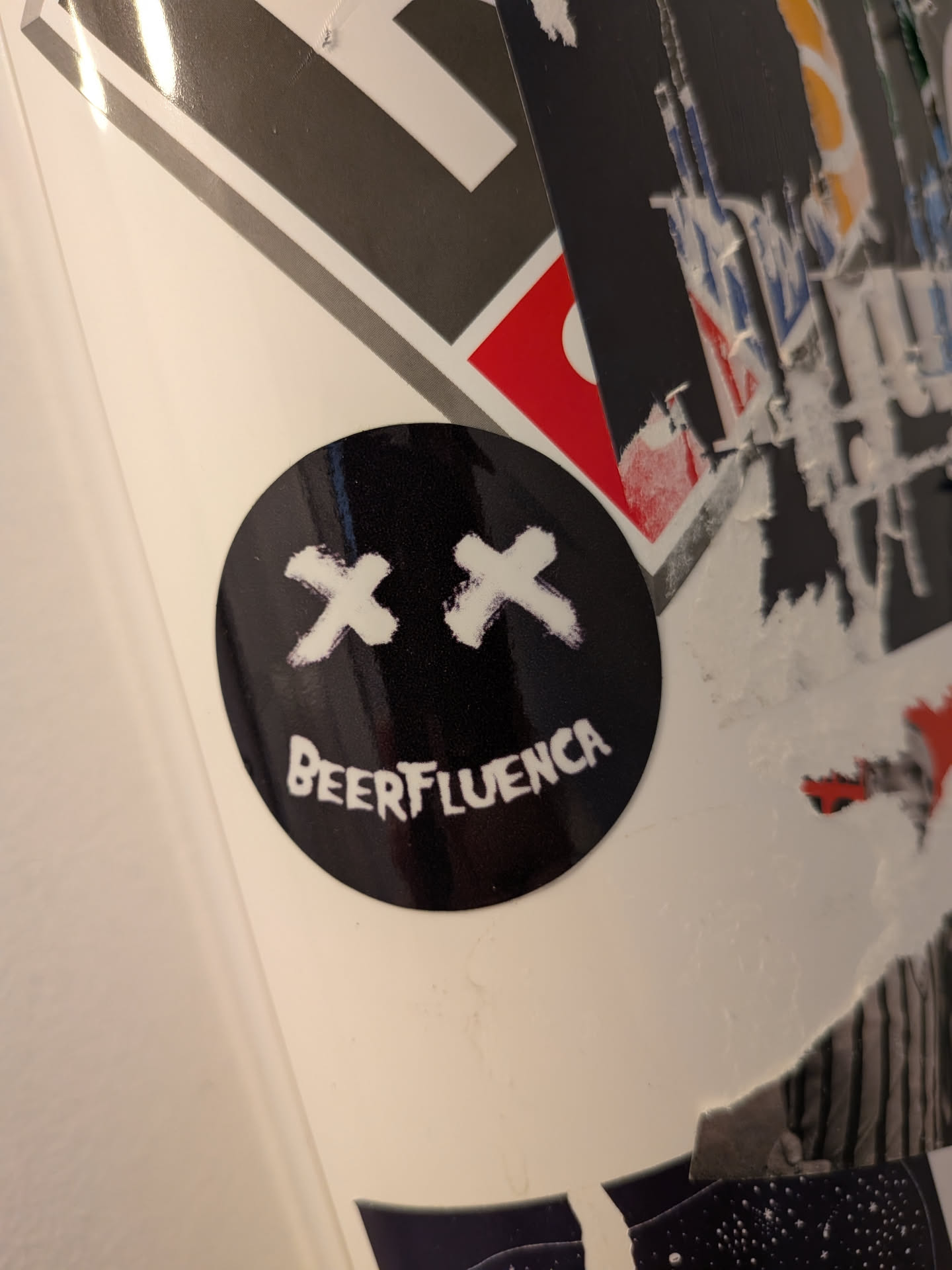 A glossy, round black sticker featuring a white graphic of two 'X's for eyes and the text 'BEERFLUENCA' curved to form a smiling mouth.