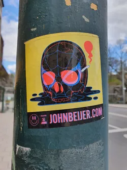 Sticker featuring a skull design with a spiderweb pattern, red eyes, and a cigarette. The skull is depicted melting, and the background is yellow. The sticker includes the website JOHNBEIJER.COM and a smiley face logo. 