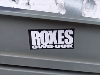 A black and white sticker with the word ROXES in bold white letters on a black background. Underneath, it says CWD.UK in smaller letters.