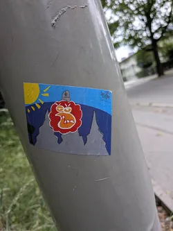 A rectangular sticker depicting an angry red character with a star-topped hat. The background features grey mountain peaks, dark blue hills, a yellow sun, and a blue sky. A small signature '2024 KOSM' is in the top right corner.