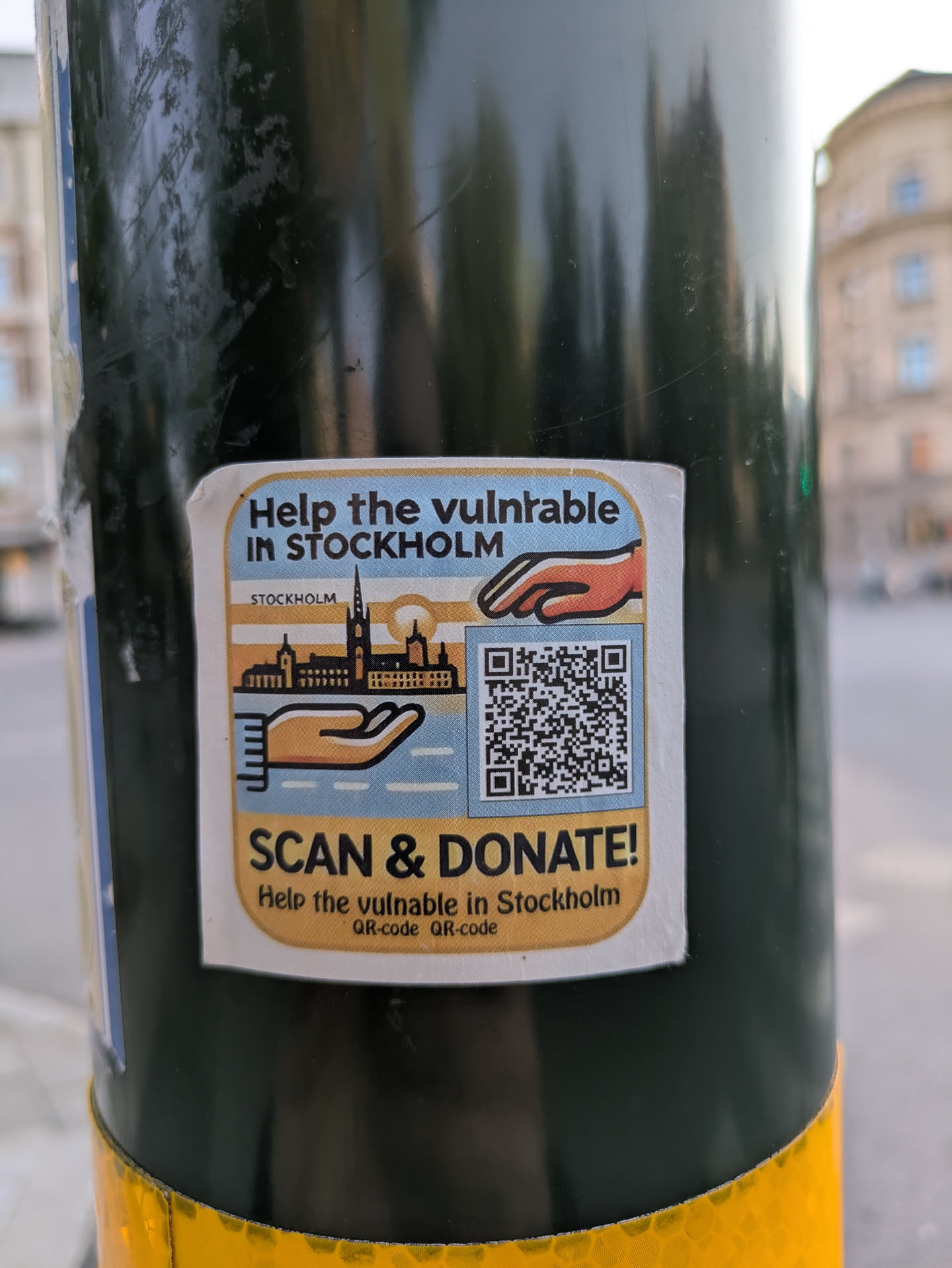 The sticker features a cityscape of Stockholm and hands, along with the text "Help the vulnerable in Stockholm" and a call to action to scan and donate. A QR code is prominently displayed for easy access to the donation platform.