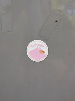 Street sticker A circular pink and white sticker showing a stylized fox standing atop a mountain peak. It features a double-ring border and shows slight wear and a small tear.