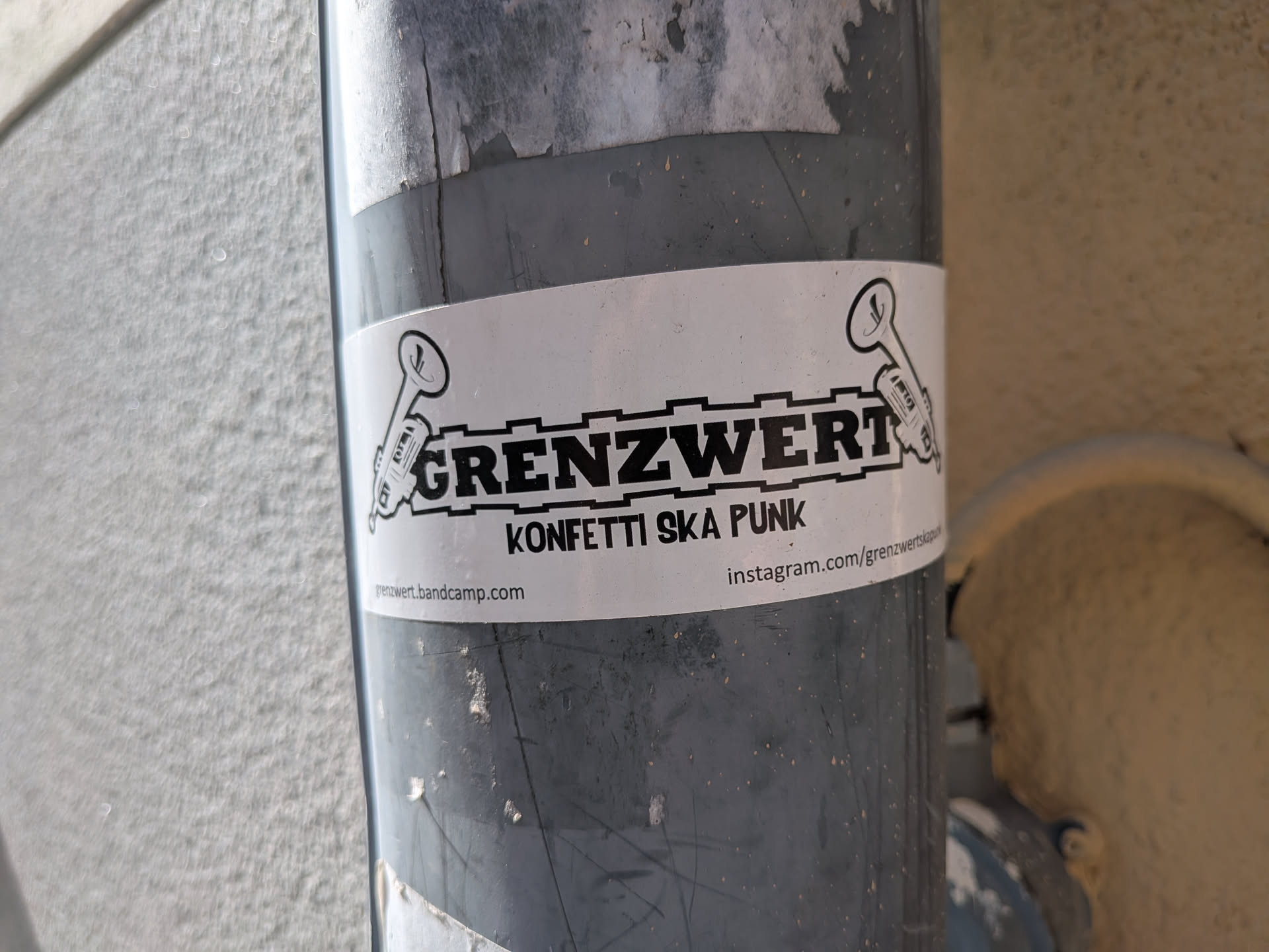 A white rectangular sticker featuring the bold black text 'GRENZWERT' inside a gear-like border, flanked by two trumpet illustrations. Below, it reads 'KONFETTI SKA PUNK' with bandcamp and Instagram links at the bottom.