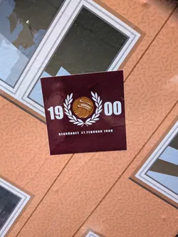 Street sticker A square maroon sticker featuring a classic brown leather football enclosed in a white laurel wreath. The year '1900' is split on either side in white bold font, with the German text 'GEGRÜNDET 27.FEBRUAR 1900' printed below.