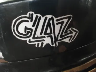 Street sticker Black and white sticker with the word GLAZ stylized in a graffiti-like font. The sticker has a slightly worn look, suggesting it may have been placed outdoors. 