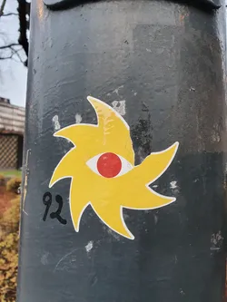 Street sticker A yellow sun with a red eye in the center. The number 92 is written below it. It's a simple yet striking design.