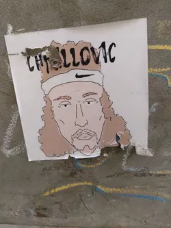 Street sticker A sticker featuring a hand-drawn illustration of tennis player Casper Ruud.  The illustration shows Ruud with his characteristic long hair and a headband.  The sticker is slightly torn at the edges.