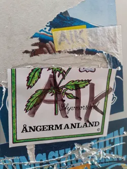 Street sticker A sticker featuring a drawing of a plant with the letters AK, the words "Glymorsrid" and "Ångermanland", and a copyright symbol. The style is reminiscent of nature-inspired designs or possibly a regional emblem.
