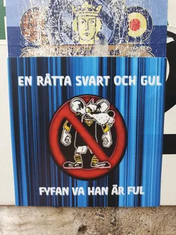 Street sticker A sticker with a cartoon rat in a black and yellow shirt. The rat is crossed out with a red circle. The text on the sticker says "En rätta svart och gul" (A black and yellow rat) and "Fyfan va han är ful" (Damn, he's ugly).