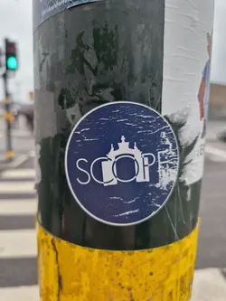 A round, dark blue sticker with the word SCOPE in a stylized font.  A small graphic of a building or castle is visible above the text. The sticker shows some wear and tear. 