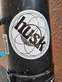 Street sticker Round black and white sticker with the word "Husk" in a stylized font.  The word "Hammocks" is smaller and underneath. A geometric design is in the background.