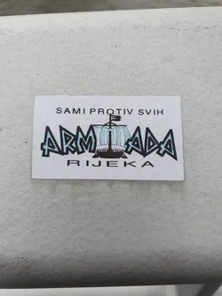 Street sticker A sticker featuring the Armada Rijeka logo, a stylized ship with text above 'SAMI PROTIV SVIH' which means 'alone against all' and below 'RIJEKA', which is the name of the city. The overall design is simple yet striking.
