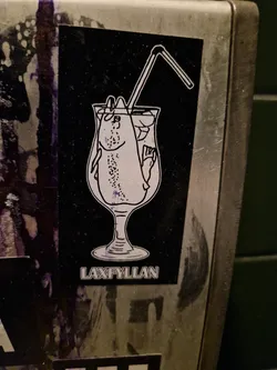 Black and white sticker of a fish in a cocktail glass with a straw. The text LAXFYLLAN is visible at the bottom.