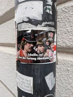 Street sticker A rectangular sticker depicting a group of young men, with one wearing a decorated hat. Includes German text and a 'Sektion Tee mit Rum' logo with Fortuna Düsseldorf shields.