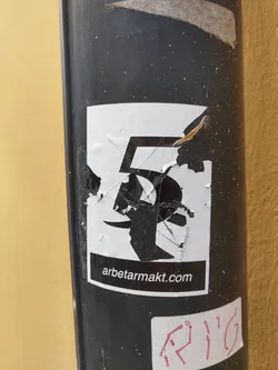 The sticker is partially damaged and shows a stylized number 5.  The website arbetarmakt.com is visible at the bottom. The sticker is affixed to a dark-colored pole.