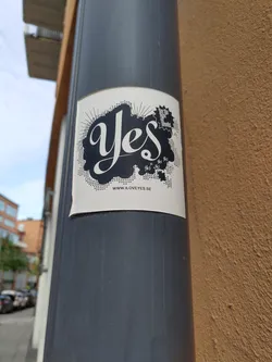 Street sticker A minimalist sticker featuring the word "Yes" in a stylized script font, set against a halftone background with burst lines.  There is a small logo or design element near the top right, and a website address at the bottom. The overall aesthetic is clean and modern.