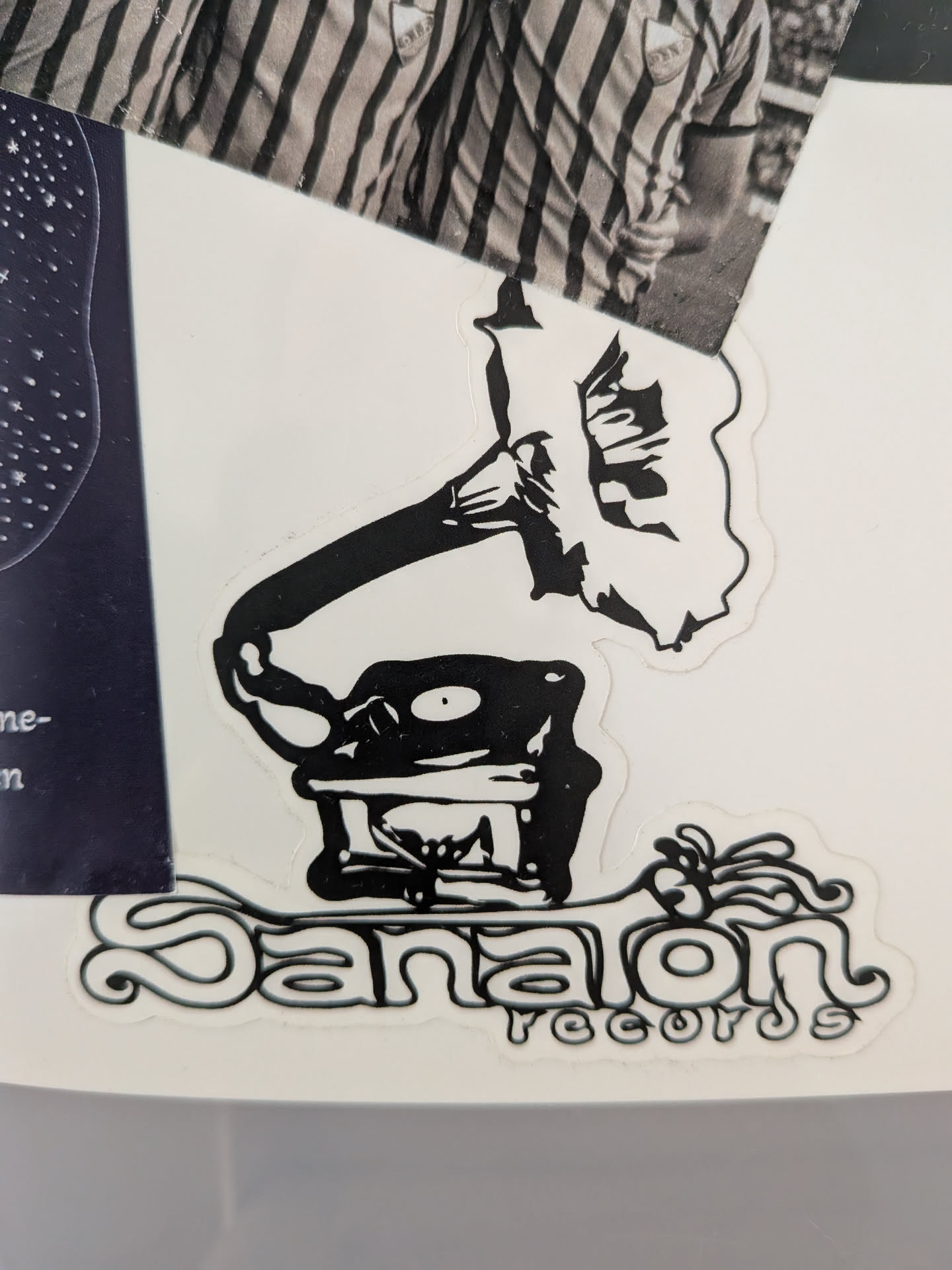 A black and white sticker featuring a stylized, somewhat anthropomorphic gramophone or phonograph. The base of the gramophone has a face-like appearance with two eyes and a mouth, and a record is visible on its turntable. The large horn of the gramophone is abstractly rendered with internal shapes. Below the illustration, the word "Sanalon" is written in a distinctive, bubbly, almost psychedelic font, followed by "records" in a smaller, rounded, stylized font. The entire design is outlined in white, creating a clear border.